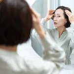 鏡を見て髪の毛を気にする日本人女性